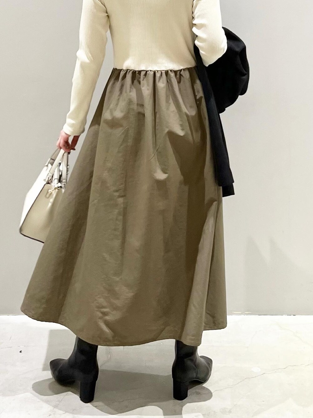 ブラック系のジャケット/アウター、グリーン系のワンピース、ホワイト系のショルダーバッグを着用したレディースの冬コーディネートの5枚目の写真