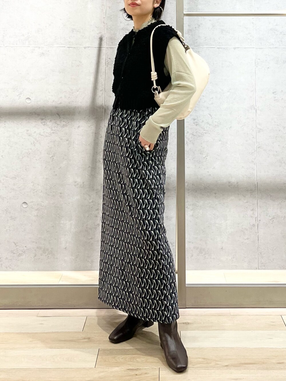 グリーン系のスカート、グリーン系のTシャツ/カットソー、ブラック系のベストを着用したレディースの秋コーディネートの3枚目の写真