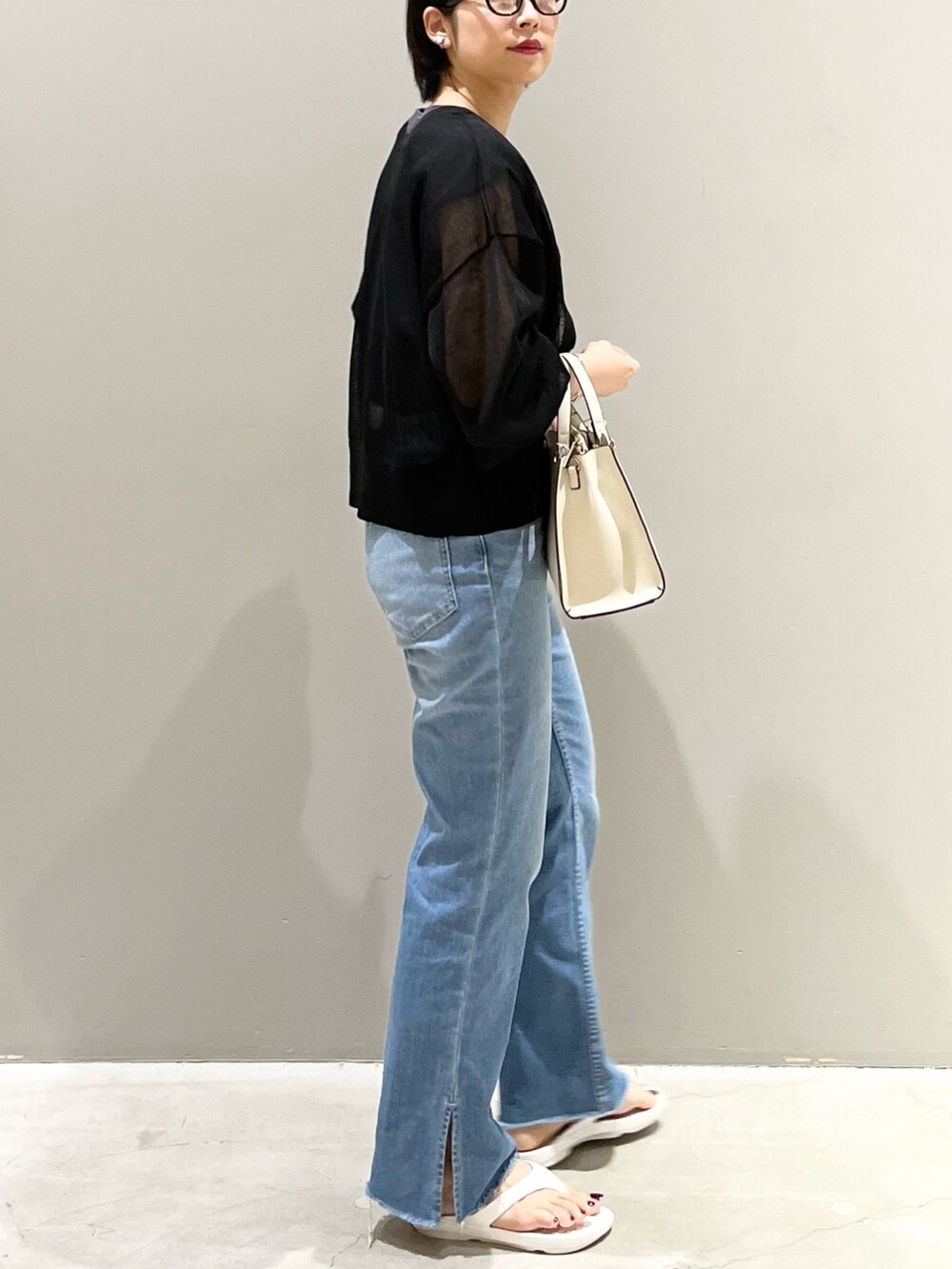 ホワイト系のサンダル、ホワイト系のショルダーバッグ、ブルー系のデニムパンツを着用したレディースの夏コーディネートの3枚目の写真