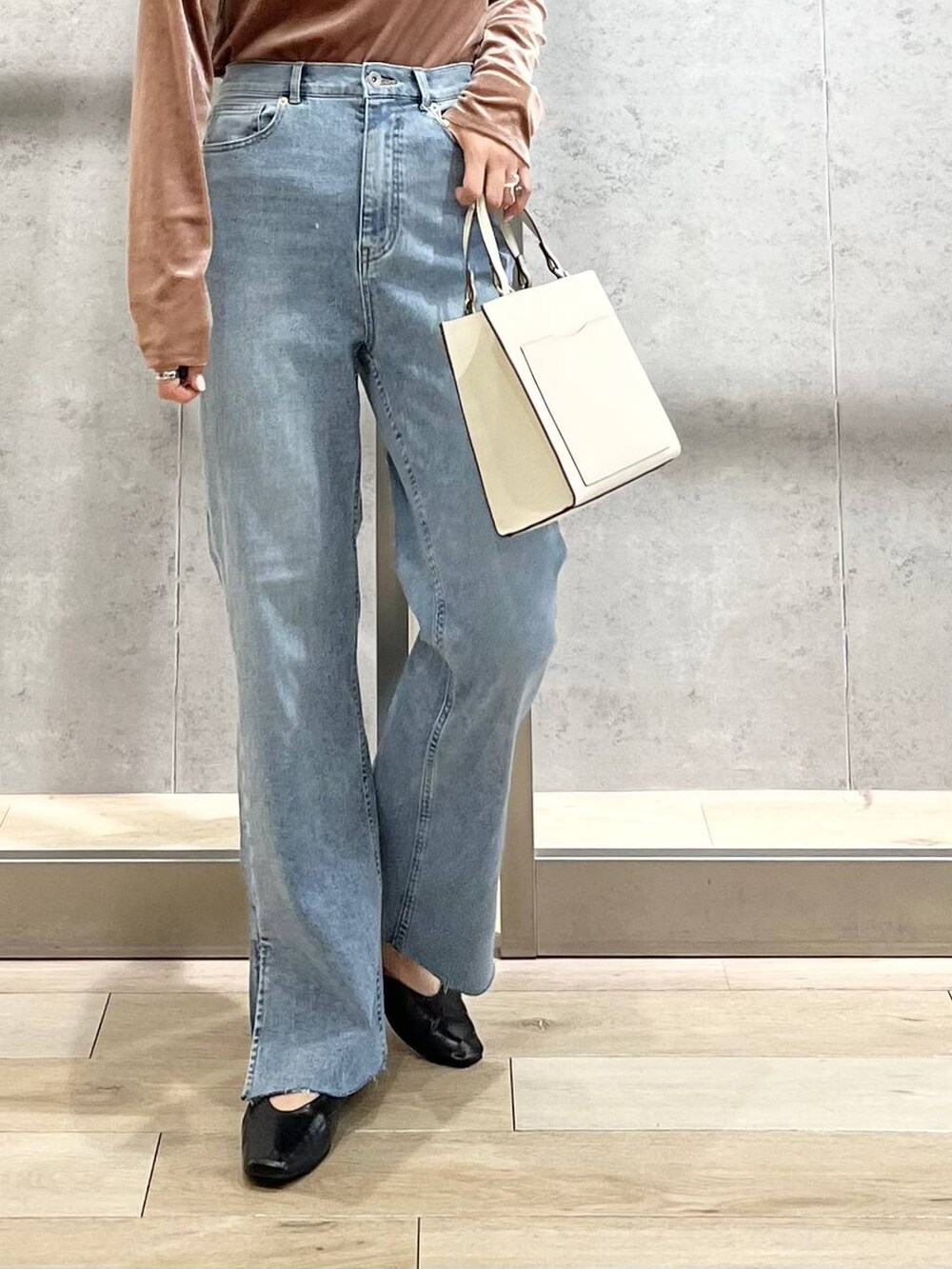 ブラック系のパンプス、ブルー系のデニムパンツ、ホワイト系のショルダーバッグを着用したレディースの秋コーディネートの5枚目の写真