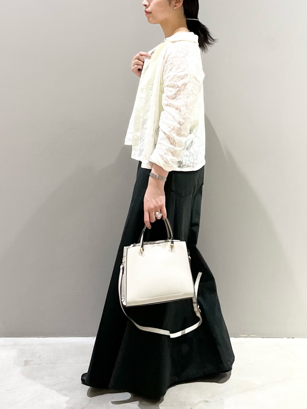 ブラック系のパンプス、グレー系のスカート、ホワイト系のショルダーバッグを着用したレディースの秋コーディネートの2枚目の写真