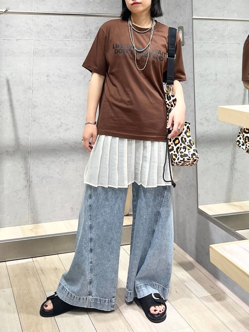 ブルー系のデニムパンツ、ブラック系のサンダル、シルバー系のネックレスを着用したレディースの夏コーディネートの4枚目の写真