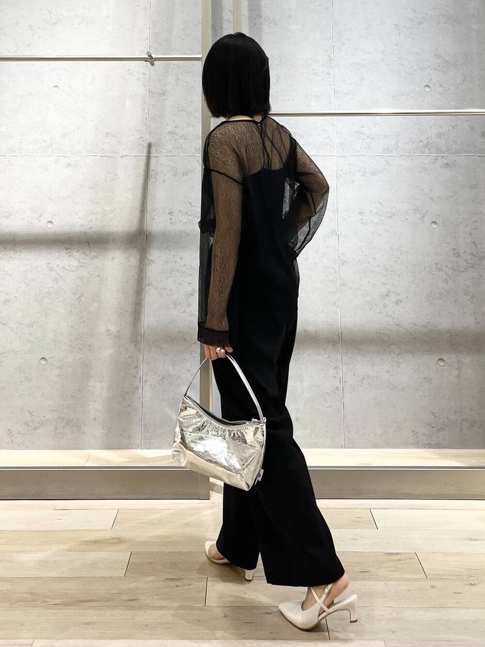 シルバー系のハンドバッグ、ブラック系のシャツ/ブラウス、ブラック系のスラックスを着用したレディースの冬コーディネートの3枚目の写真