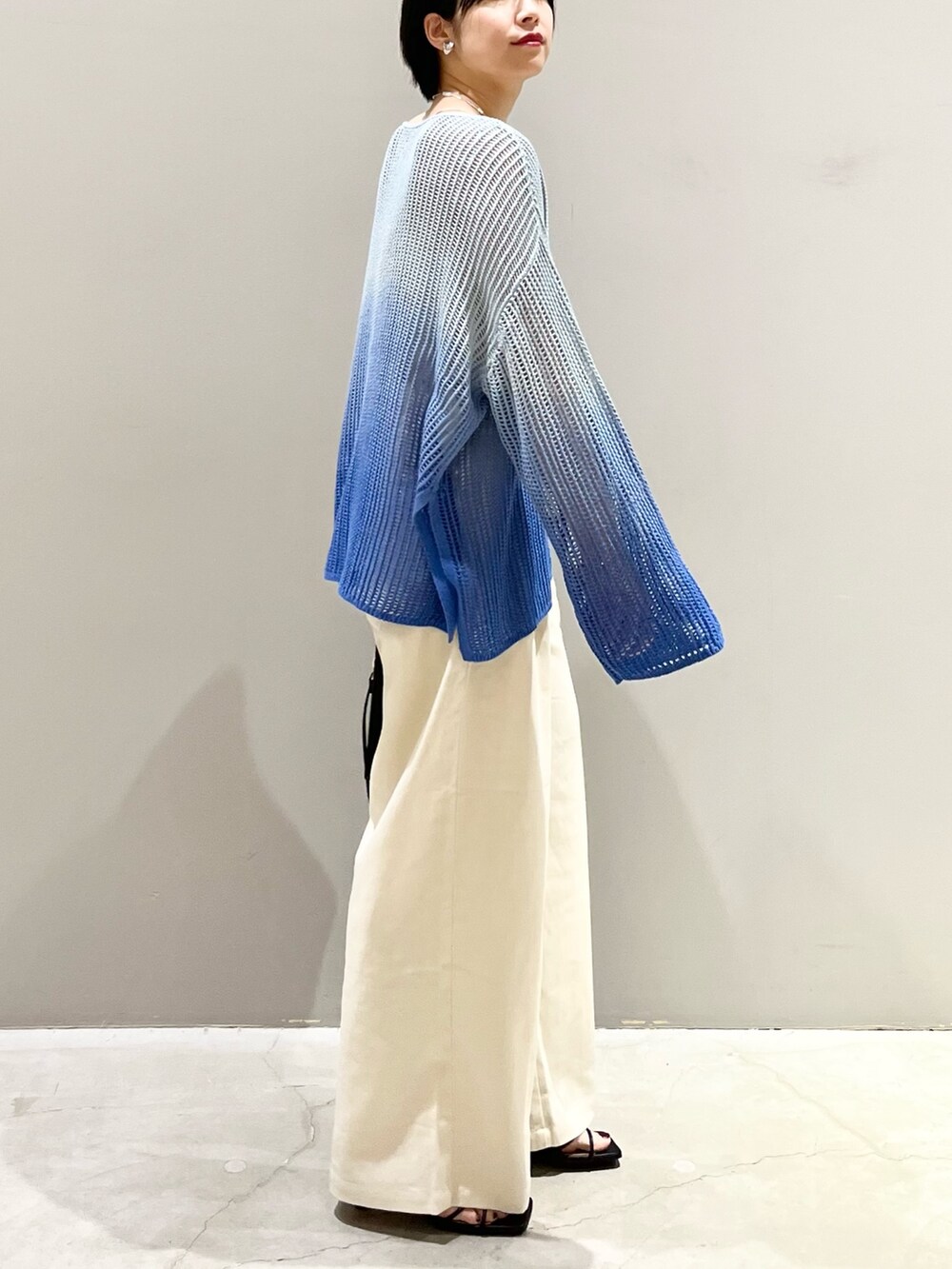 ブルー系のニット/セーター、ブラック系のショルダーバッグ、ブラック系のサンダルを着用したレディースの春コーディネートの4枚目の写真