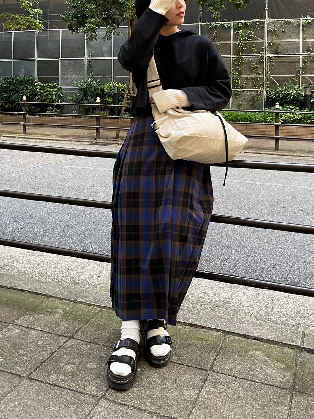 ブラック系のパーカー、ブルー系のスカート、ホワイト系のショルダーバッグを着用したレディースの秋コーディネートの2枚目の写真