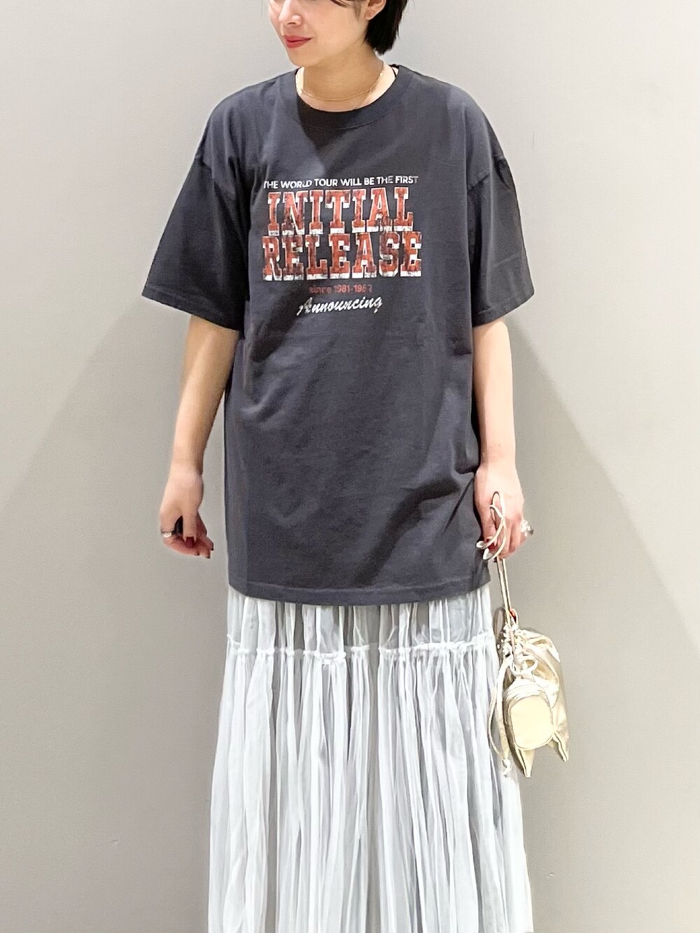 ブラック系のデニムパンツ、グレー系のスカート、ゴールド系のハンドバッグを着用したレディースの夏コーディネートの3枚目の写真