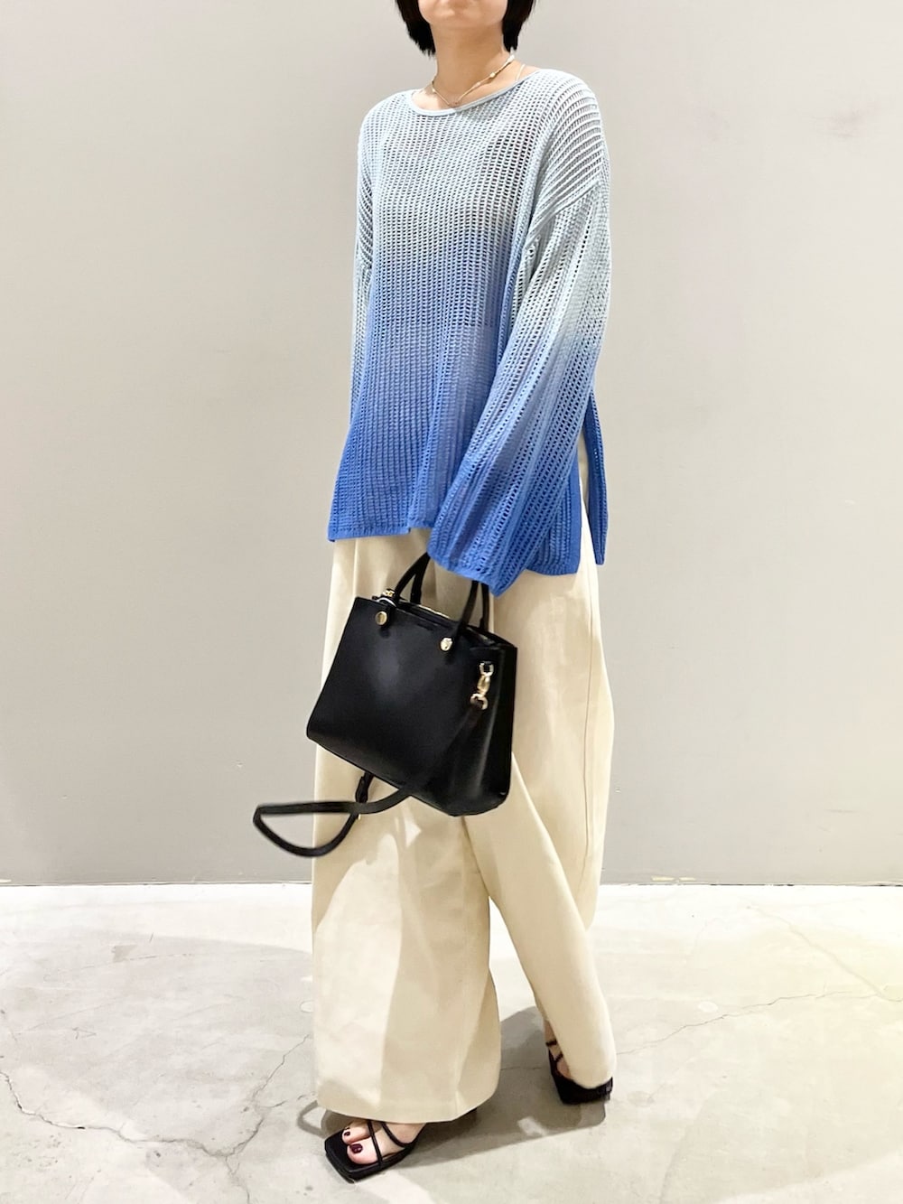 ブルー系のニット/セーター、ブラック系のショルダーバッグ、ブラック系のサンダルを着用したレディースの春コーディネートの5枚目の写真