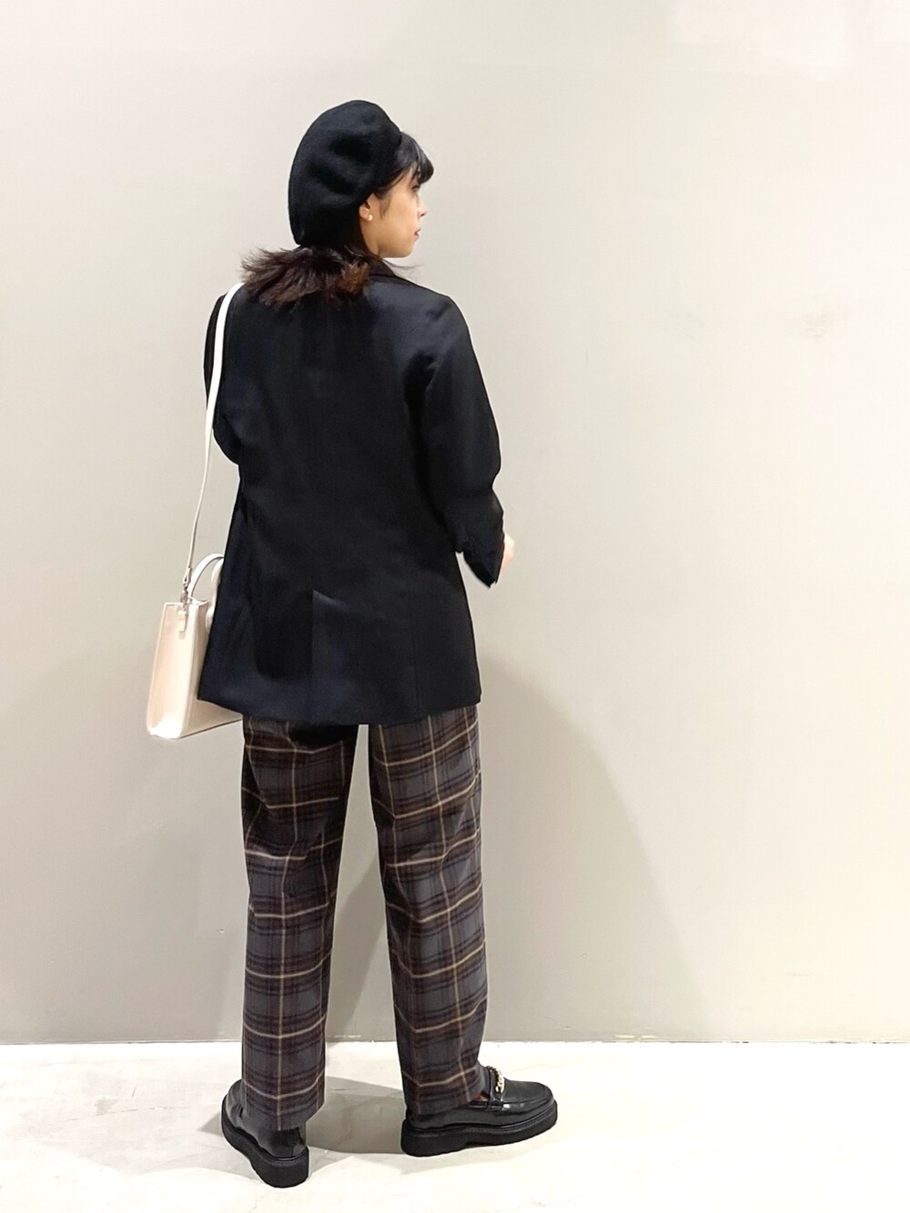 ブラウン系のスラックス、ブラック系のローファー、ホワイト系のショルダーバッグを着用したレディースの秋コーディネートの4枚目の写真