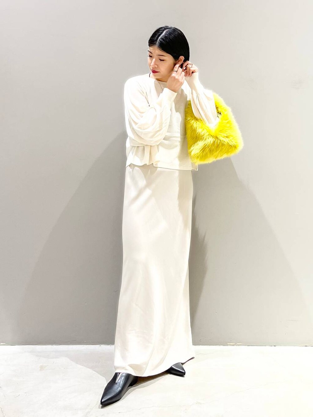 ブラック系のキャミソール、ホワイト系のニット/セーター、イエロー系のハンドバッグを着用したレディースの秋コーディネートの2枚目の写真