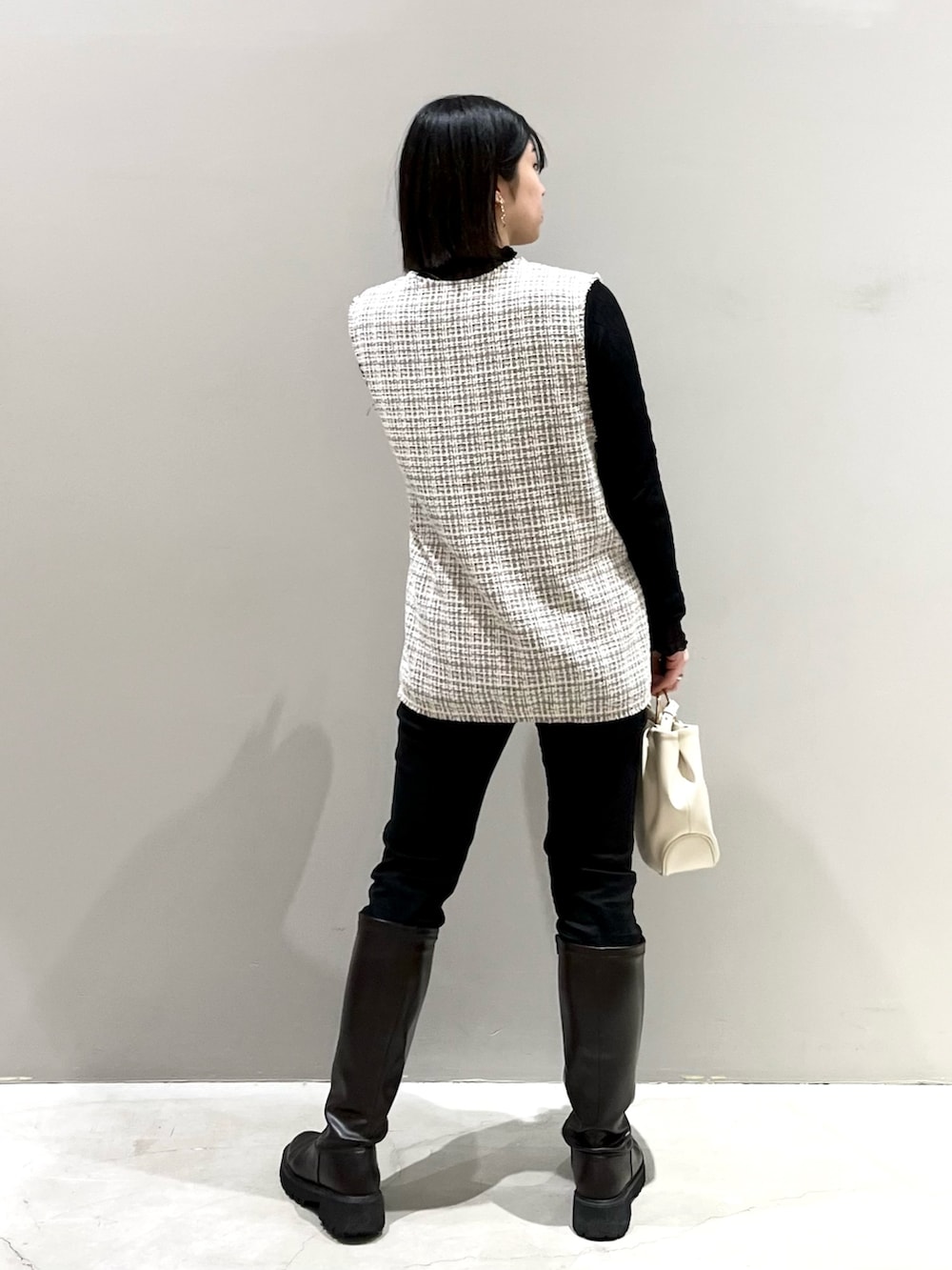 ブラウン系のブーツ、ブラック系のその他パンツ、ホワイト系のバッグを着用したレディースの春コーディネートの4枚目の写真