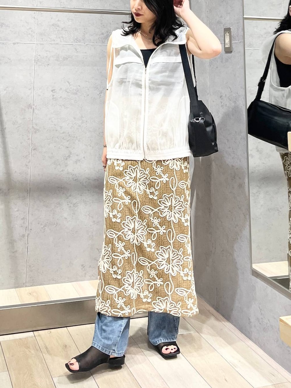 ブラック系のショルダーバッグ、ブルー系のデニムパンツ、ブラック系のサンダルを着用したレディースの春コーディネートの4枚目の写真