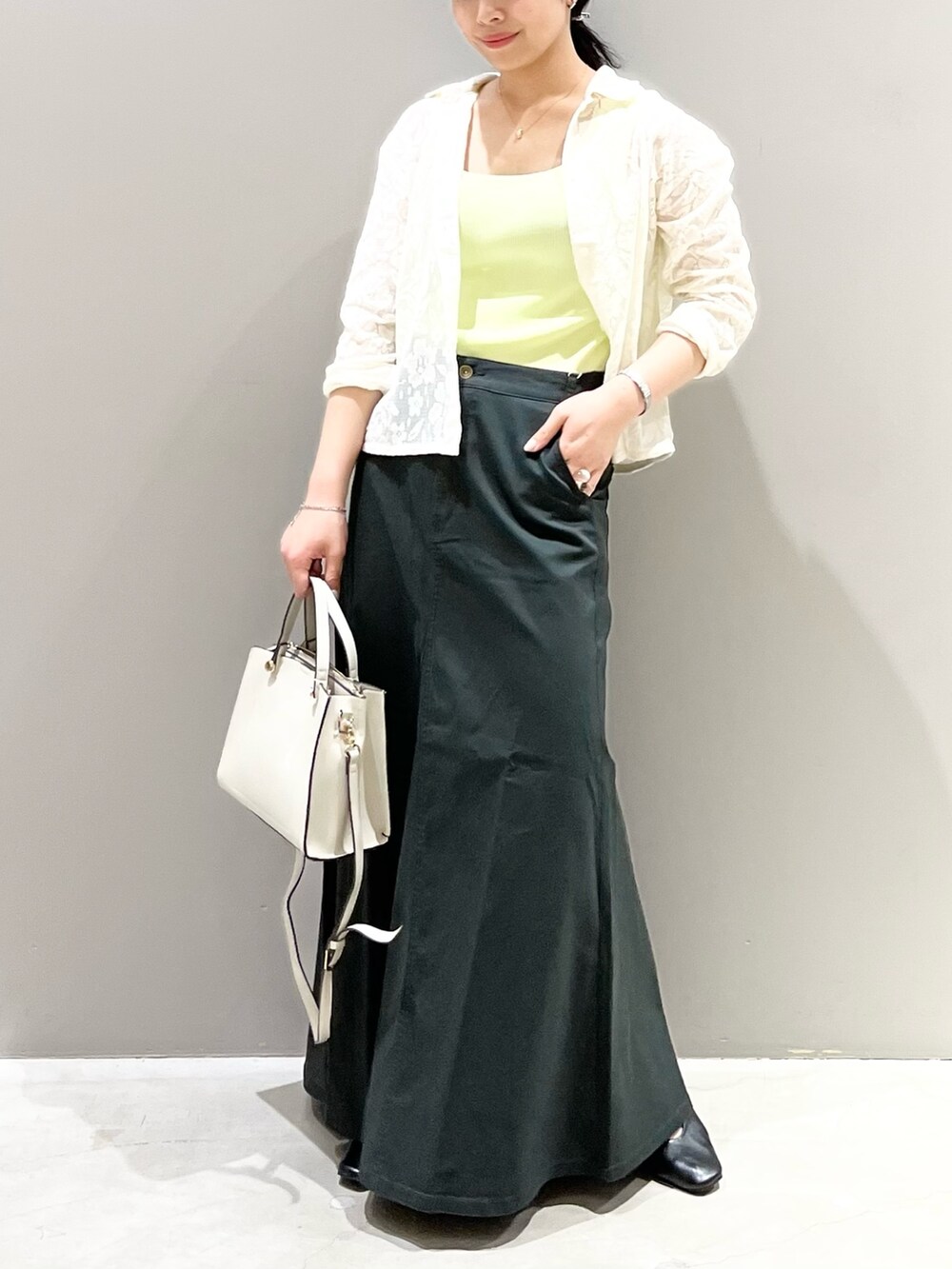 ブラック系のパンプス、グレー系のスカート、ホワイト系のショルダーバッグを着用したレディースの秋コーディネートの3枚目の写真