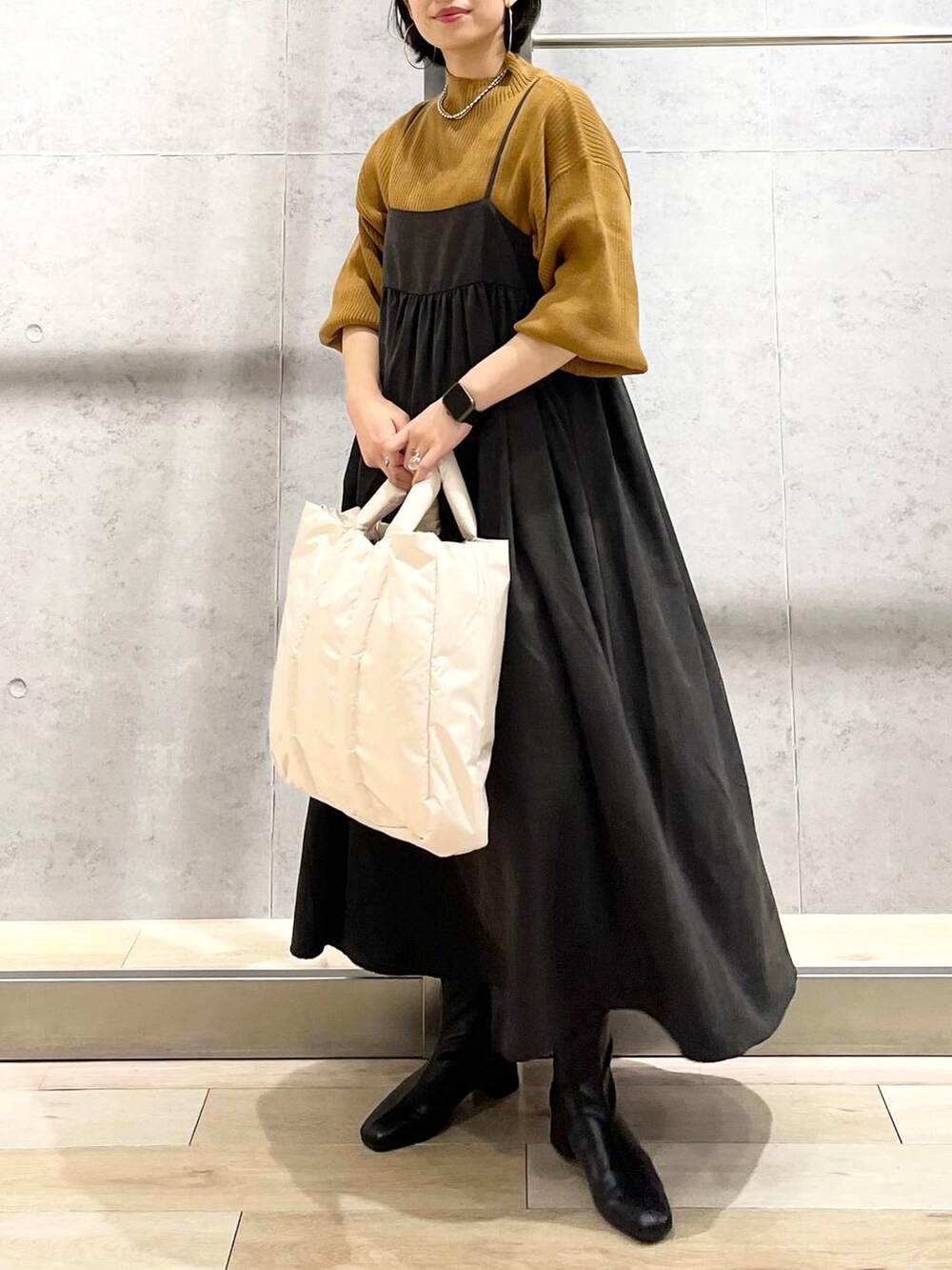 ブラウン系のニット/セーター、ホワイト系のショルダーバッグ、ブラック系のブーツを着用したレディースの秋コーディネートの4枚目の写真