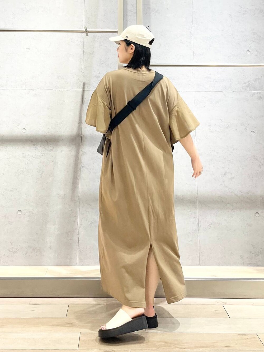 ベージュ系のワンピース、ブラック系のクラッチバッグ、ホワイト系のサンダルを着用したレディースの夏コーディネートの6枚目の写真