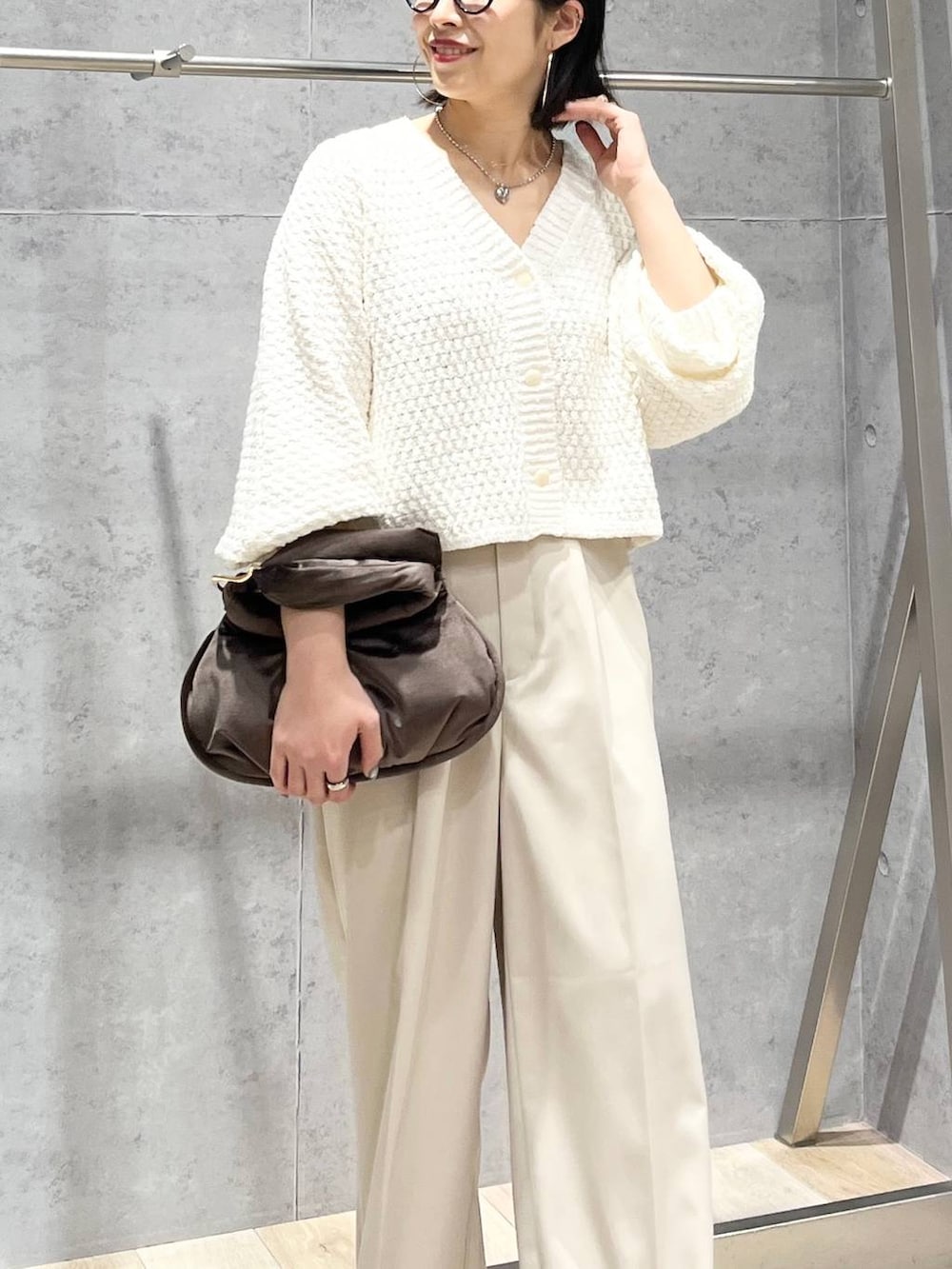 ブラウン系のハンドバッグ、グレー系のパンプス、ホワイト系のカーディガン/ボレロを着用したレディースの冬コーディネートの2枚目の写真