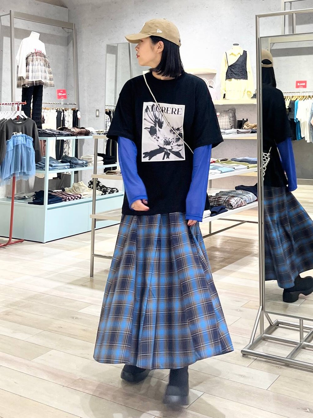 シルバー系のショルダーバッグ、ブラック系のレインシューズ、ブラック系のTシャツ/カットソーを着用したレディースの秋コーディネートの2枚目の写真