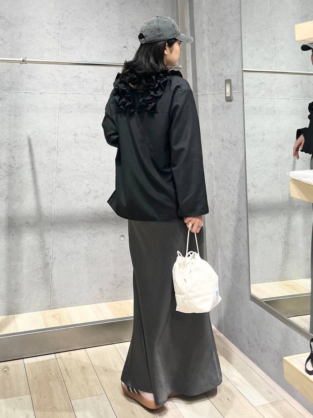 グレー系のスカート、ホワイト系のショルダーバッグ、ブラック系のキャップを着用したレディースの春コーディネートの8枚目の写真