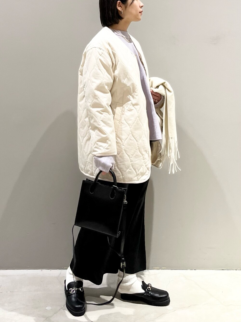 ブラック系のスカート、ブラック系のショルダーバッグ、ブラック系のローファーを着用したレディースの冬コーディネートの3枚目の写真