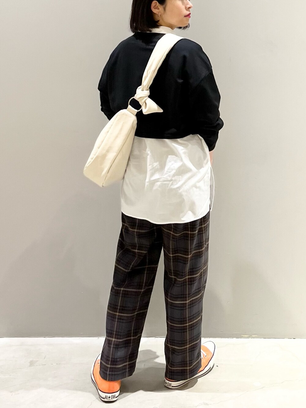 オレンジ系のスニーカー、ブラウン系のスラックス、ホワイト系のバッグを着用したレディースの春コーディネートの3枚目の写真