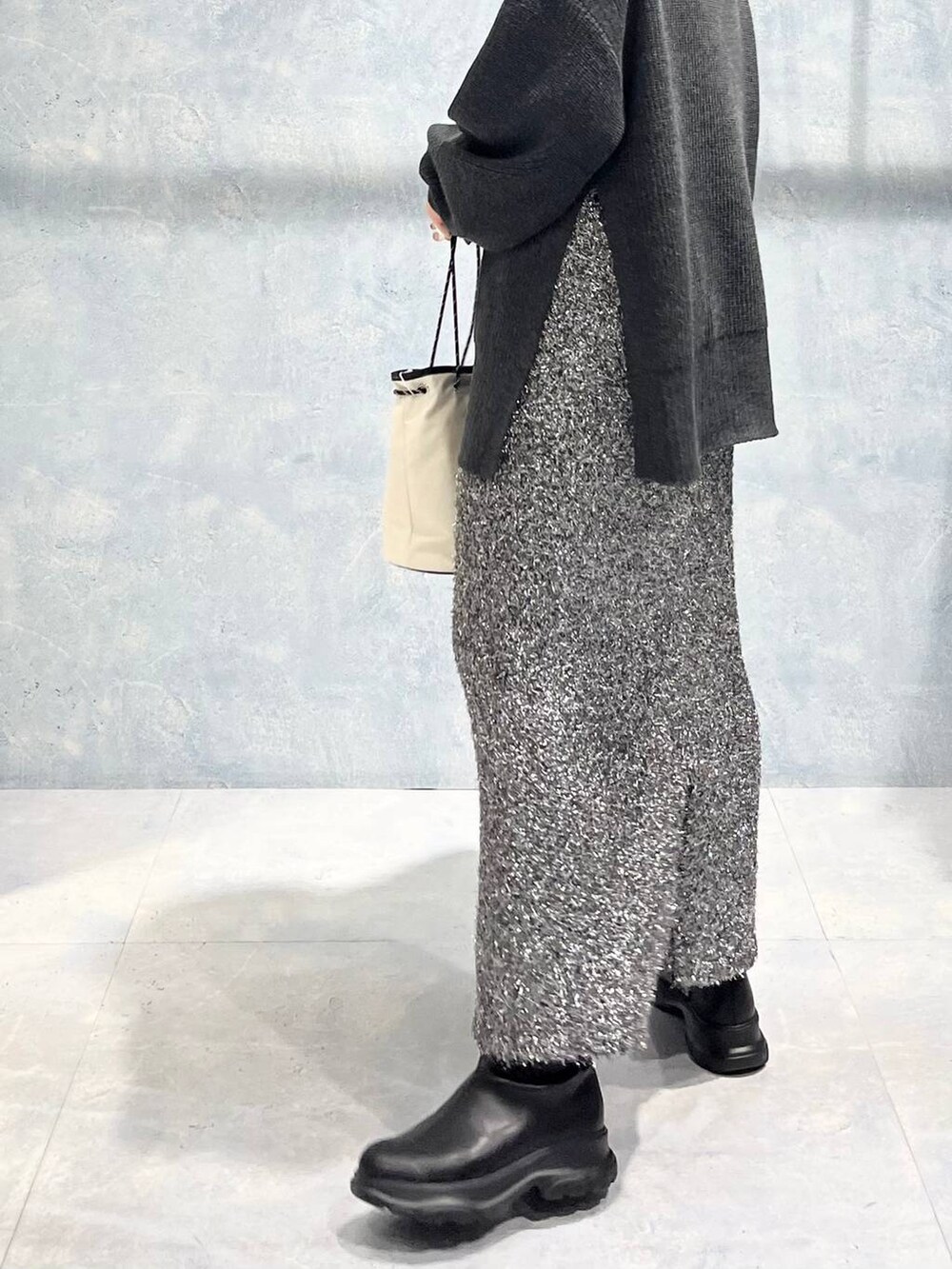 グレー系のTシャツ/カットソー、ブラック系のブーツ、ブラック系のスカートを着用したレディースの冬コーディネートの7枚目の写真