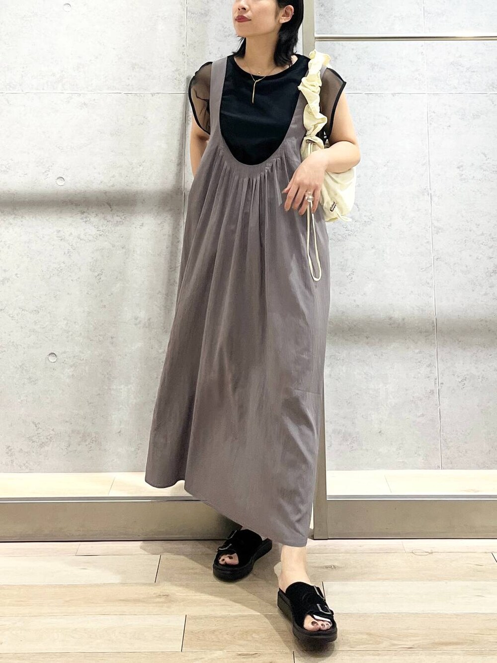 ブラック系のサンダル、グレー系のジャンパースカート、ホワイト系のショルダーバッグを着用したレディースの夏コーディネートの5枚目の写真
