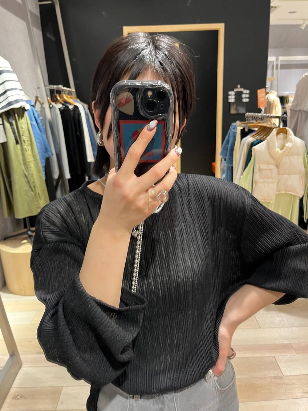 シルバー系のハンドバッグ、ブラック系のサンダル、グレー系のデニムパンツを着用したレディースの春コーディネートの2枚目の写真