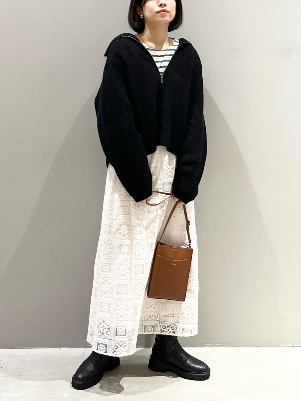 ブラウン系のショルダーバッグ、ホワイト系のスカート、ブラック系のブーツを着用したレディースの冬コーディネートの5枚目の写真