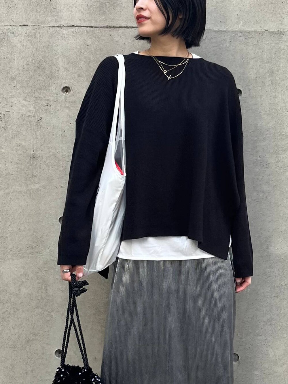 ブラック系のニット/セーター、ホワイト系のTシャツ/カットソー、シルバー系のスカートを着用したレディースの秋コーディネートの4枚目の写真