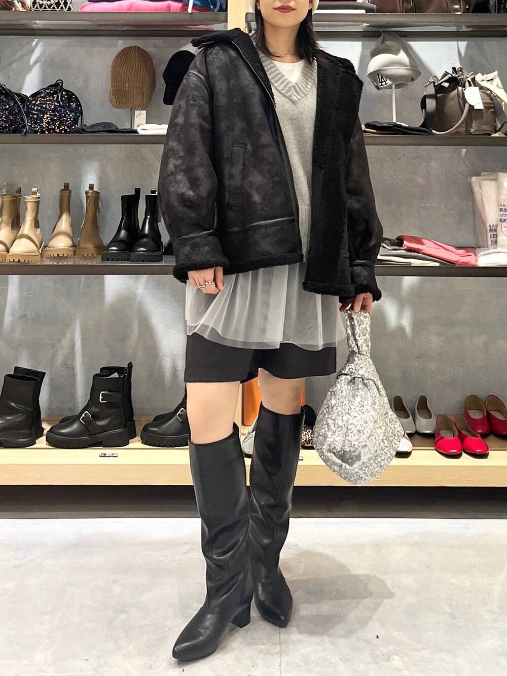 グレー系のニット/セーター、ブラック系のその他アウター、ホワイト系のTシャツ/カットソーを着用したレディースの秋コーディネートの6枚目の写真