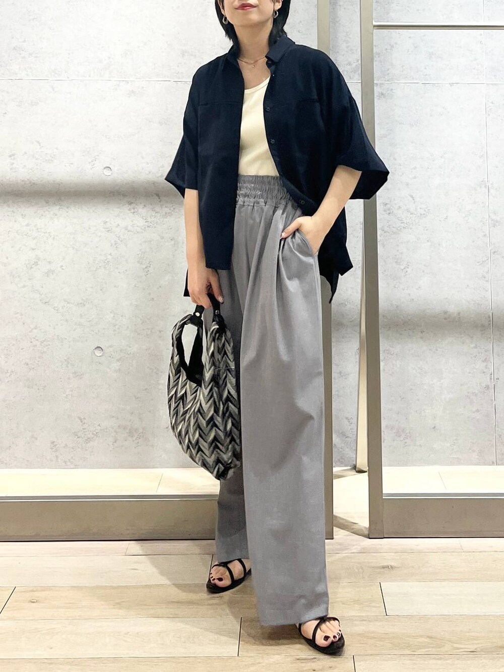 ブラック系のサンダル、ブラック系のハンドバッグ、ホワイト系のタンクトップを着用したレディースの夏コーディネートの2枚目の写真