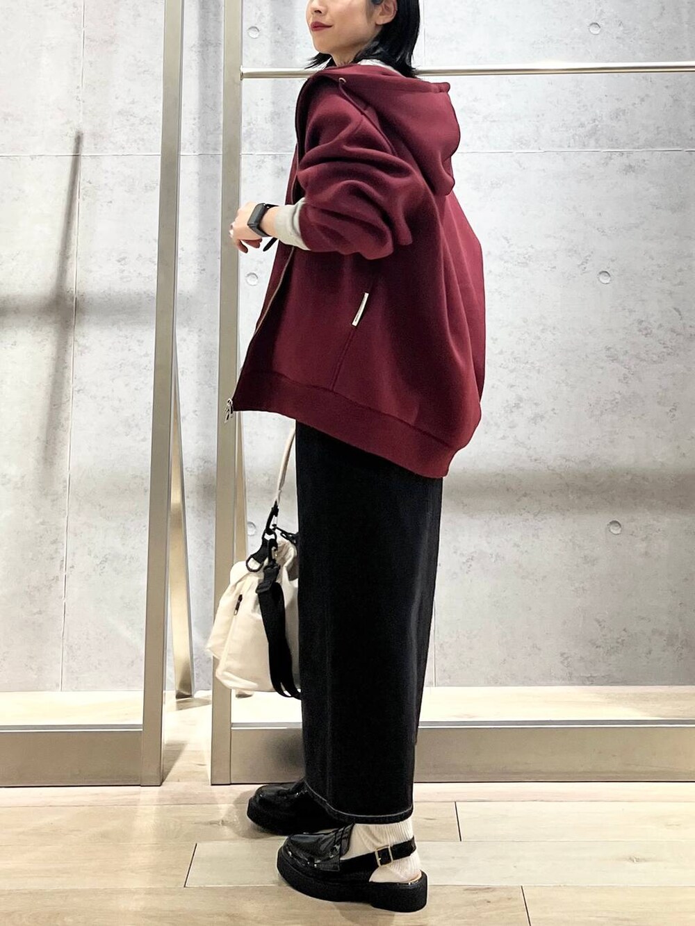 ホワイト系のショルダーバッグ、レッド系のパーカー、ブラック系のデニムスカートを着用したレディースの冬コーディネートの6枚目の写真