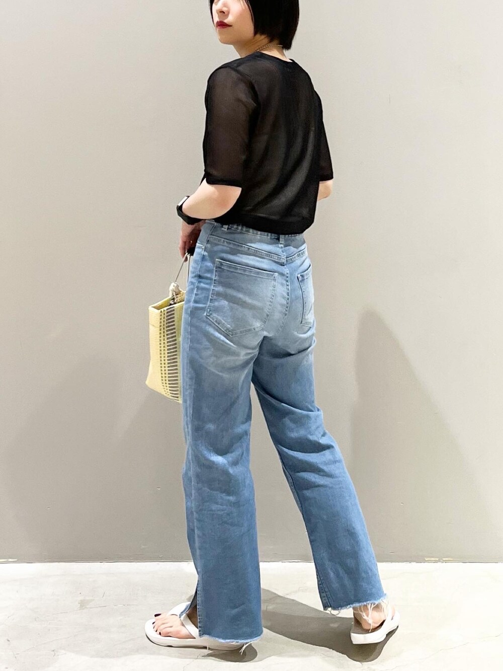 イエロー系のトートバッグ、ブルー系のデニムパンツ、ホワイト系のサンダルを着用したレディースの夏コーディネートの3枚目の写真