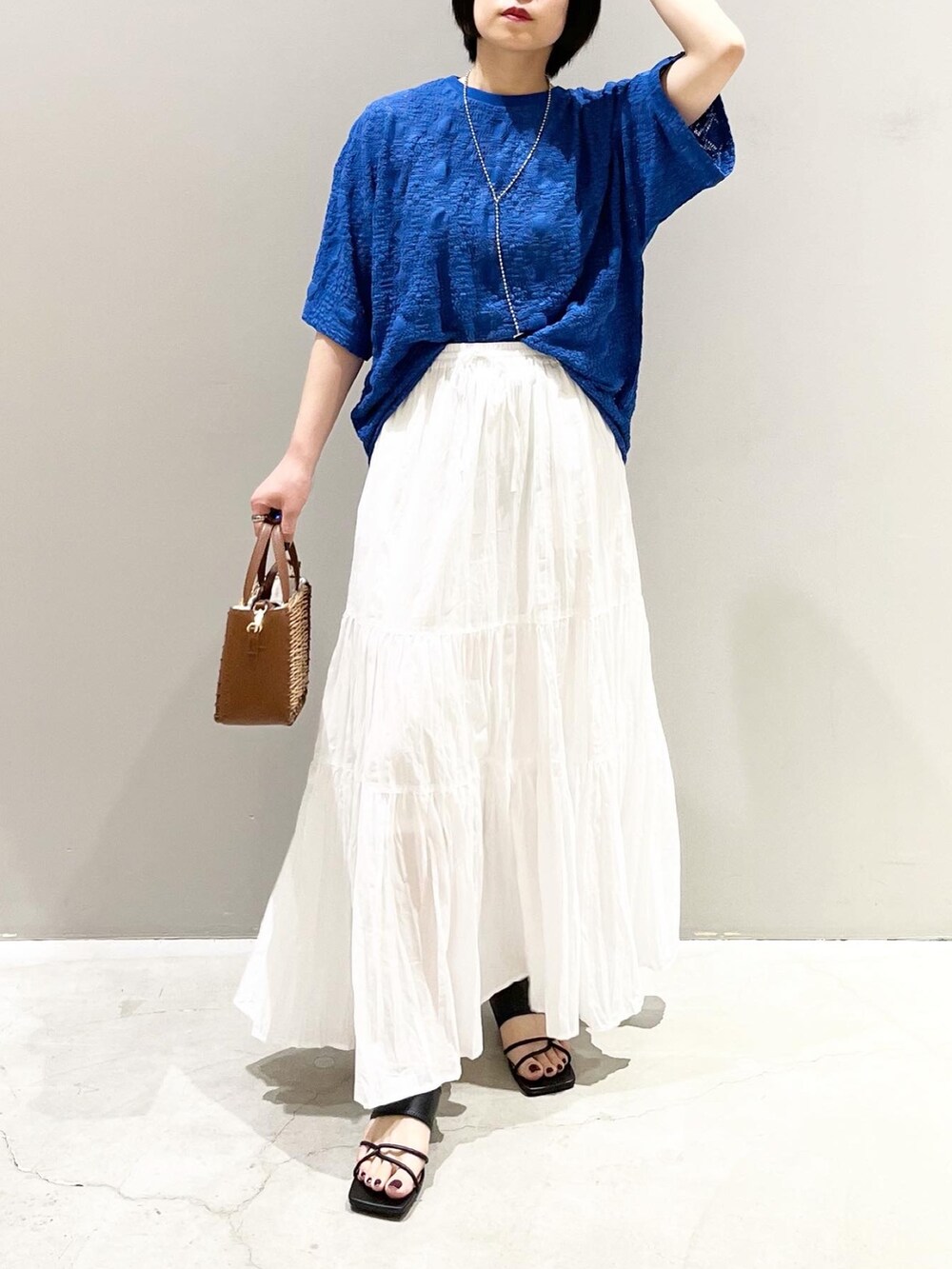 ブラック系のサンダル、ブラウン系のショルダーバッグ、ホワイト系のスカートを着用したレディースの夏コーディネートの4枚目の写真