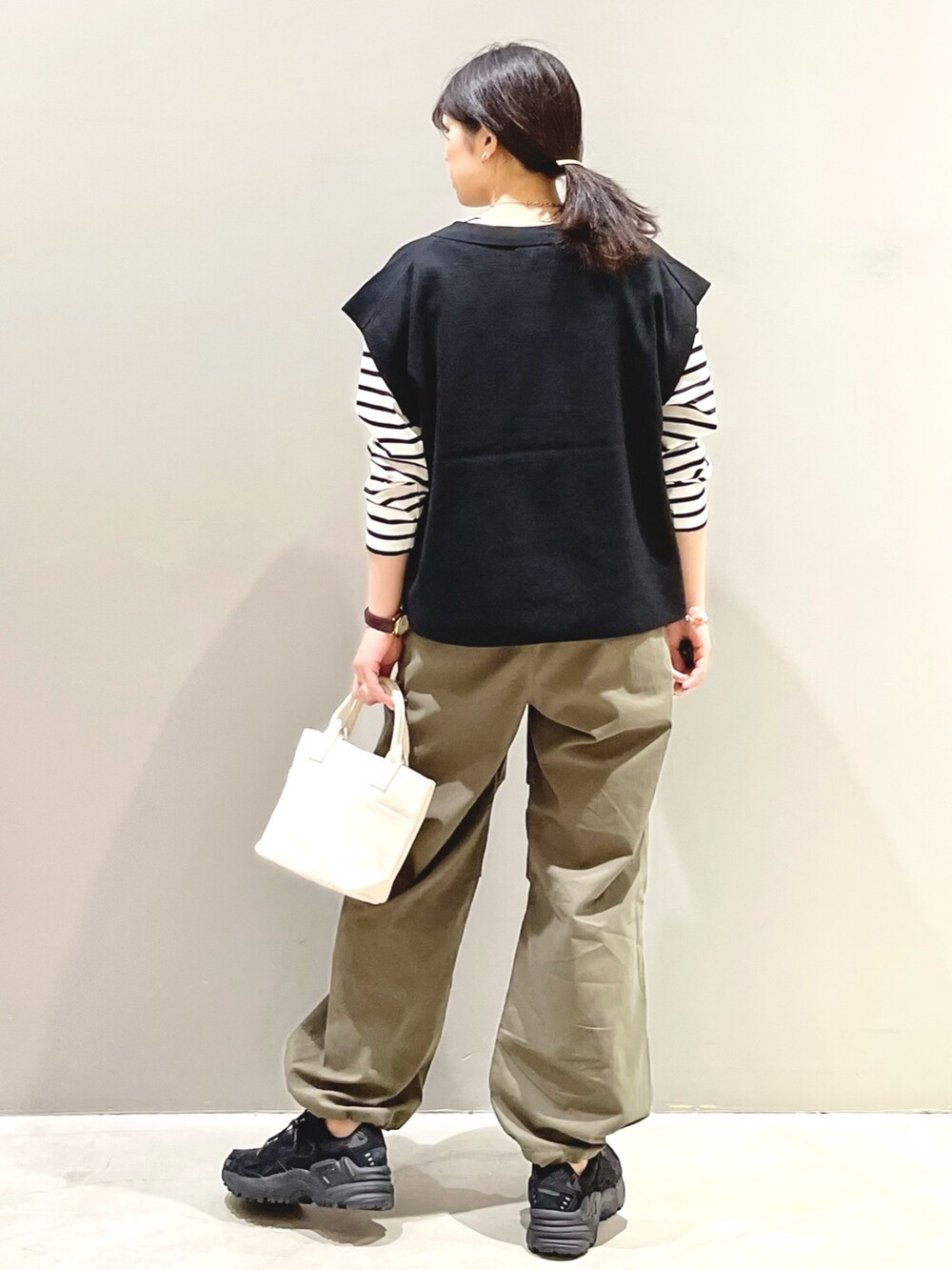 ブラック系のスニーカー、グリーン系のカーゴパンツ、ホワイト系のトートバッグを着用したレディースの秋コーディネートの3枚目の写真