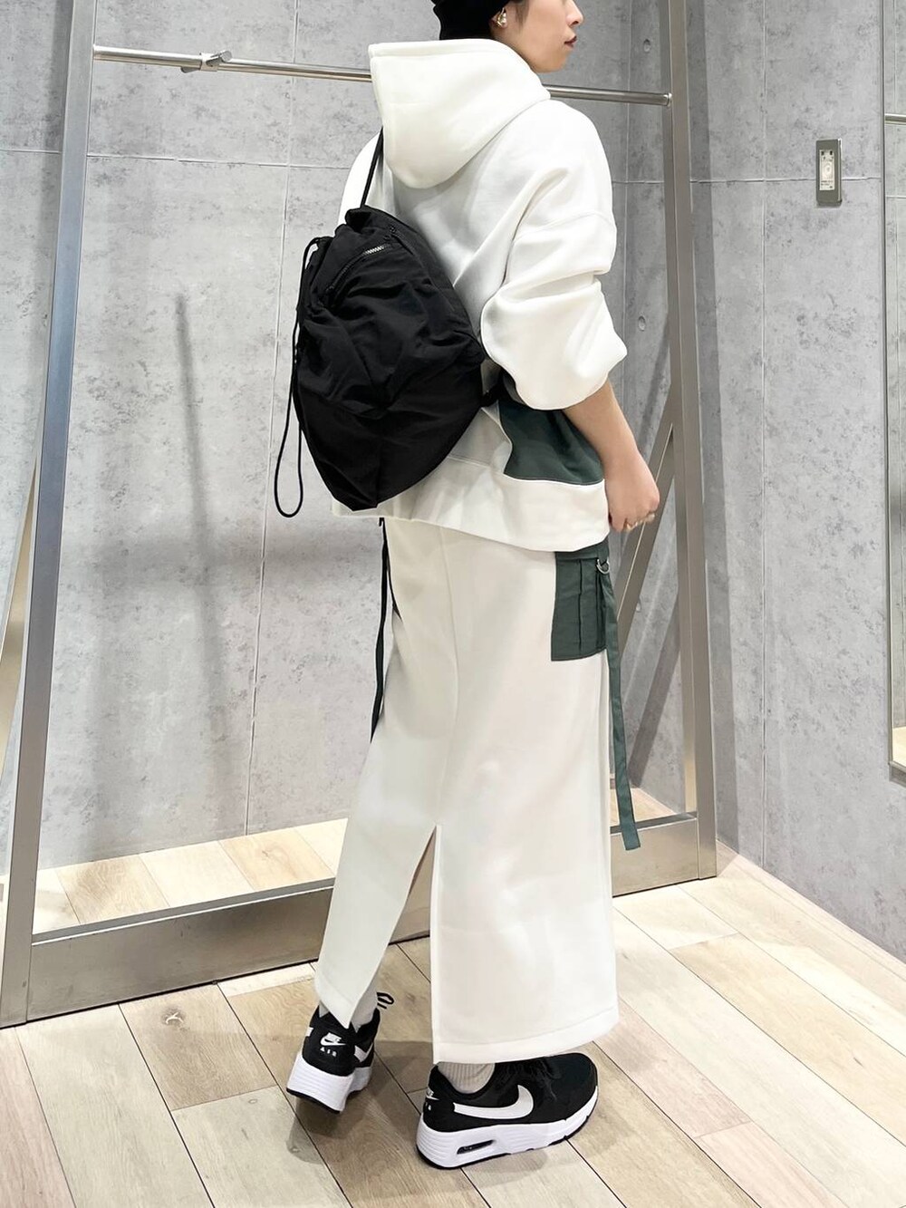 ブラック系のショルダーバッグ、ホワイト系のスカート、ホワイト系のパーカーを着用したレディースの冬コーディネートの4枚目の写真