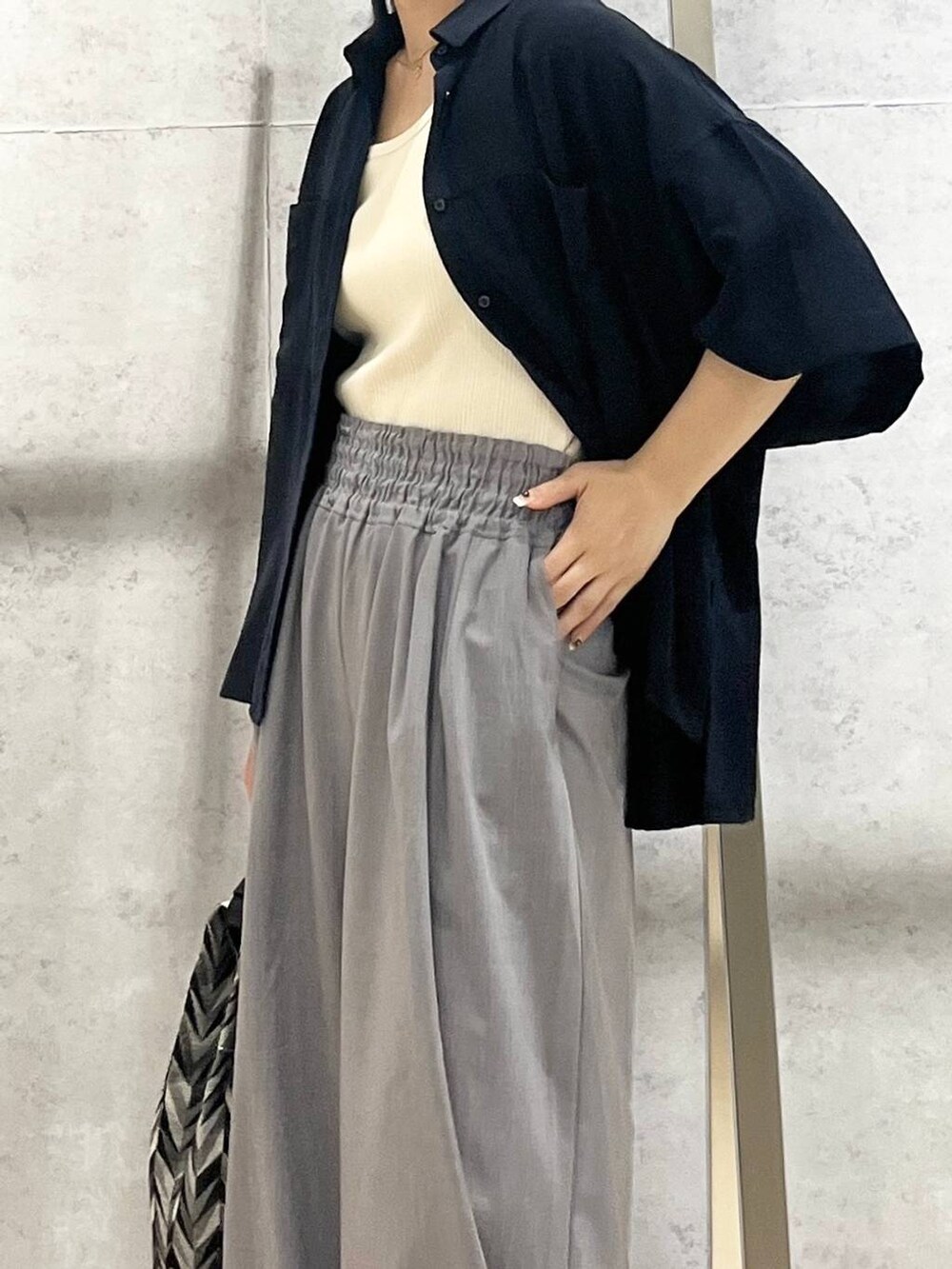 ブラック系のサンダル、ブラック系のハンドバッグ、ホワイト系のタンクトップを着用したレディースの夏コーディネートの3枚目の写真