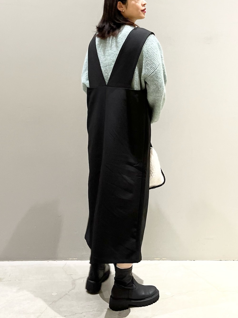 ホワイト系のバッグ、ブラック系のブーツ、グリーン系のニット/セーターを着用したレディースの冬コーディネートの3枚目の写真