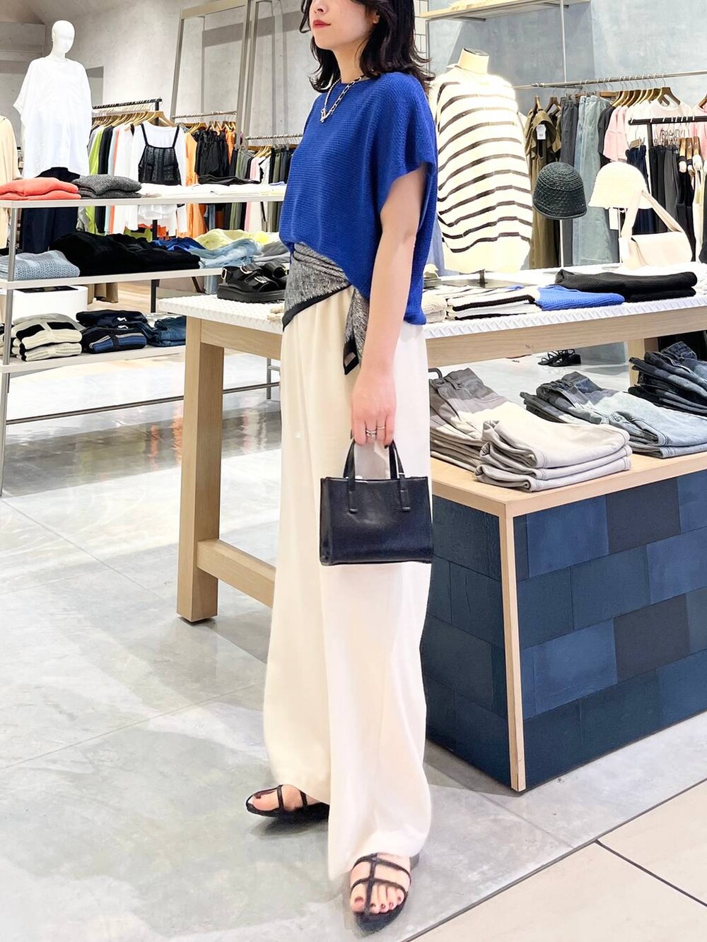 ブルー系のニット/セーター、ホワイト系のその他パンツ、ブラック系のサンダルを着用したレディースの春コーディネートの5枚目の写真