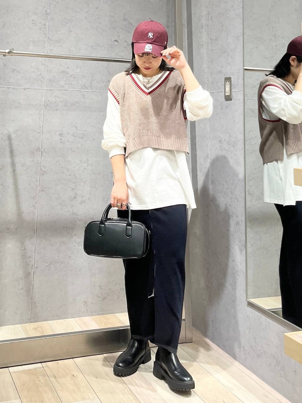 ブラック系のボストンバッグ、ブラック系のブーツ、ブラック系のスカートを着用したレディースの秋コーディネートの2枚目の写真