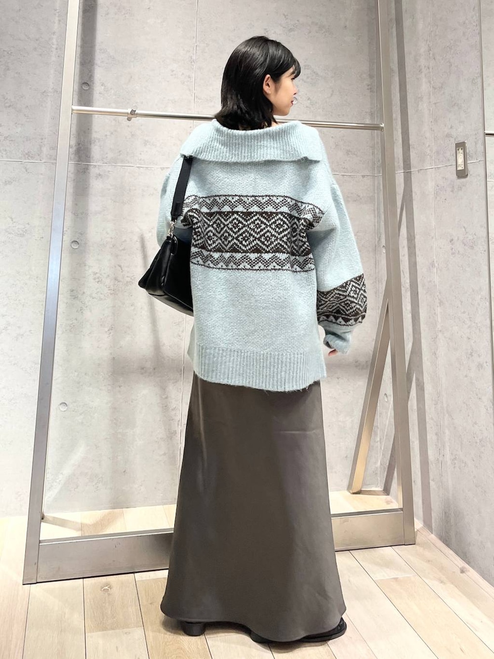 ブラック系のショルダーバッグ、グレー系のスカート、ブラック系のローファーを着用したレディースの秋コーディネートの4枚目の写真