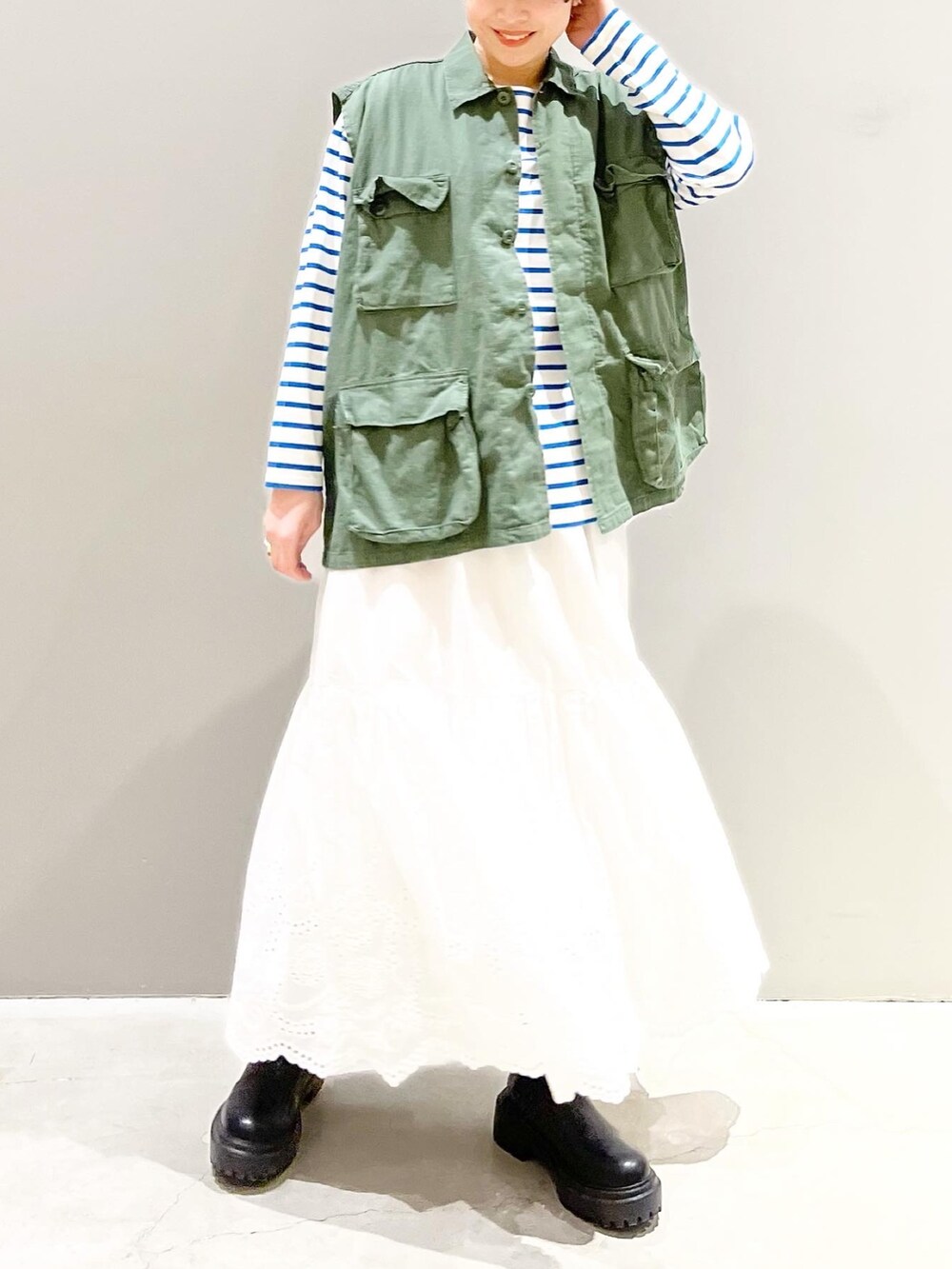 ブラック系のブーツ、ブルー系のTシャツ/カットソー、グリーン系のベストを着用したレディースの春コーディネートの5枚目の写真