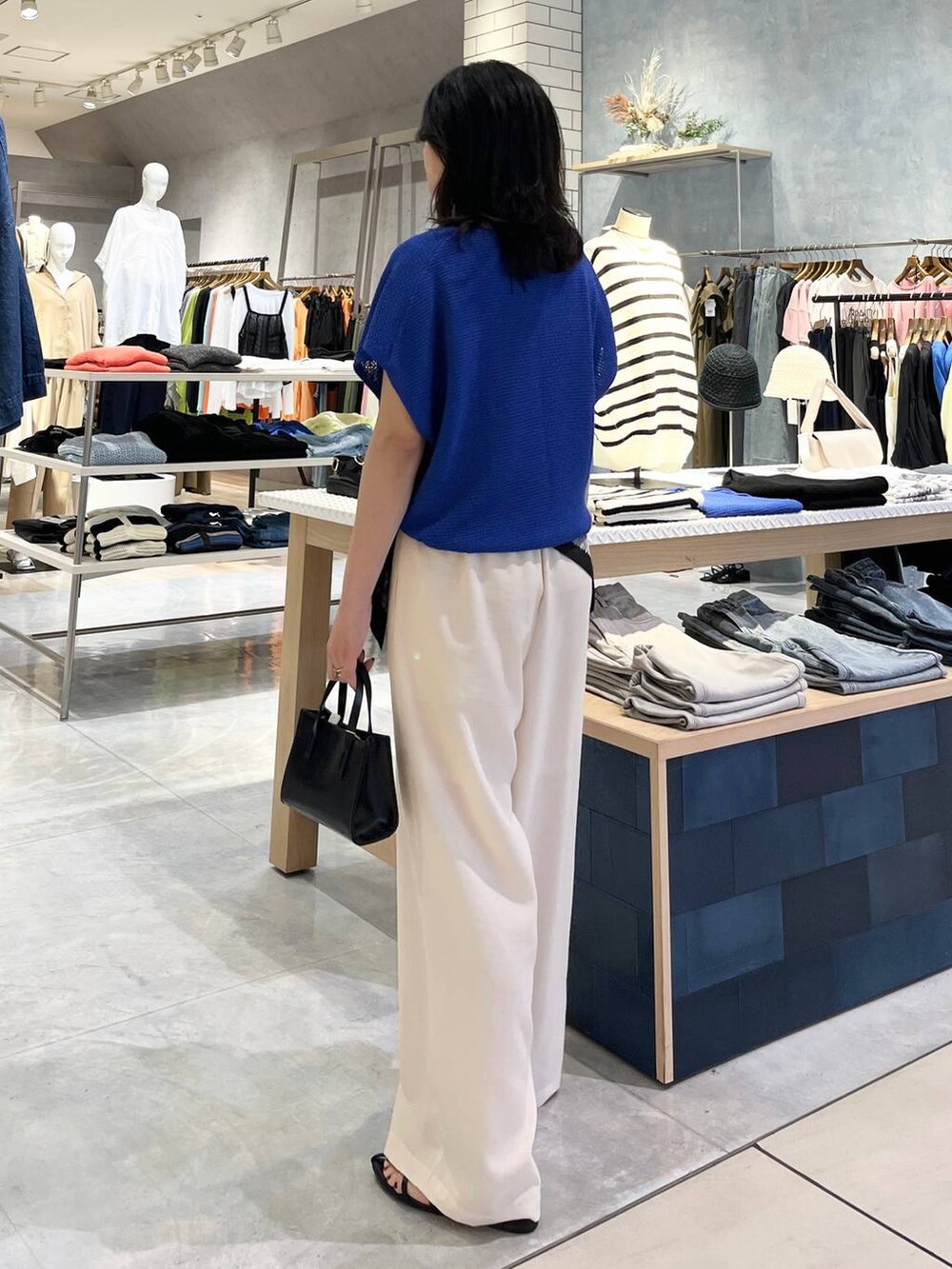 ブルー系のニット/セーター、ホワイト系のその他パンツ、ブラック系のサンダルを着用したレディースの春コーディネートの6枚目の写真