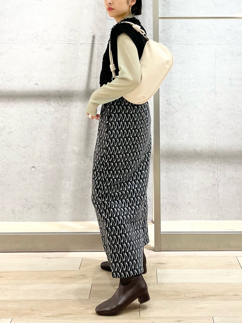 グリーン系のスカート、グリーン系のTシャツ/カットソー、ブラック系のベストを着用したレディースの秋コーディネートの4枚目の写真