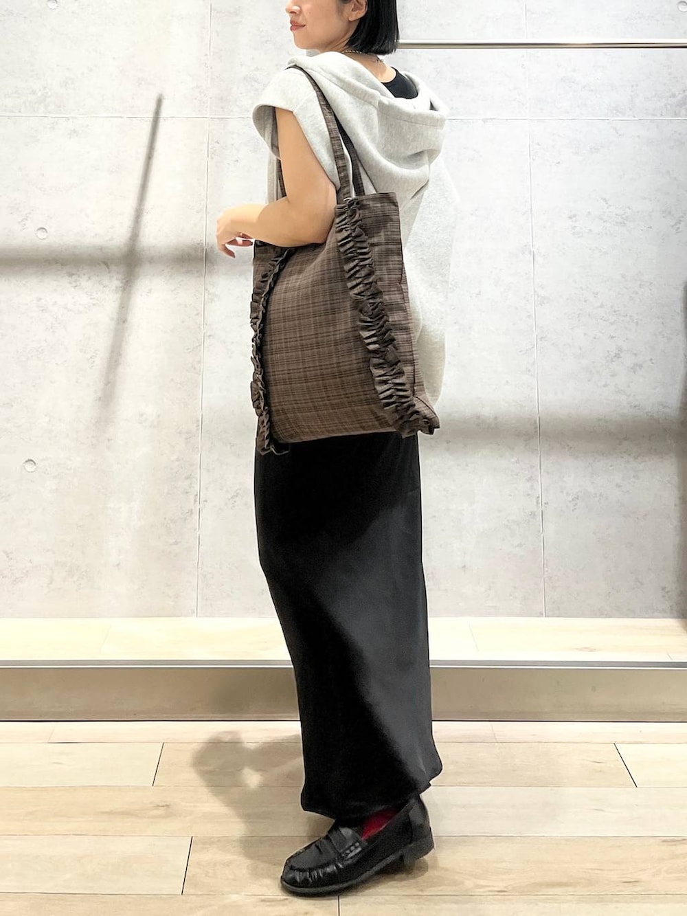 ブラック系のスカート、ブラウン系のトートバッグ、グレー系のベストを着用したレディースの秋コーディネートの2枚目の写真