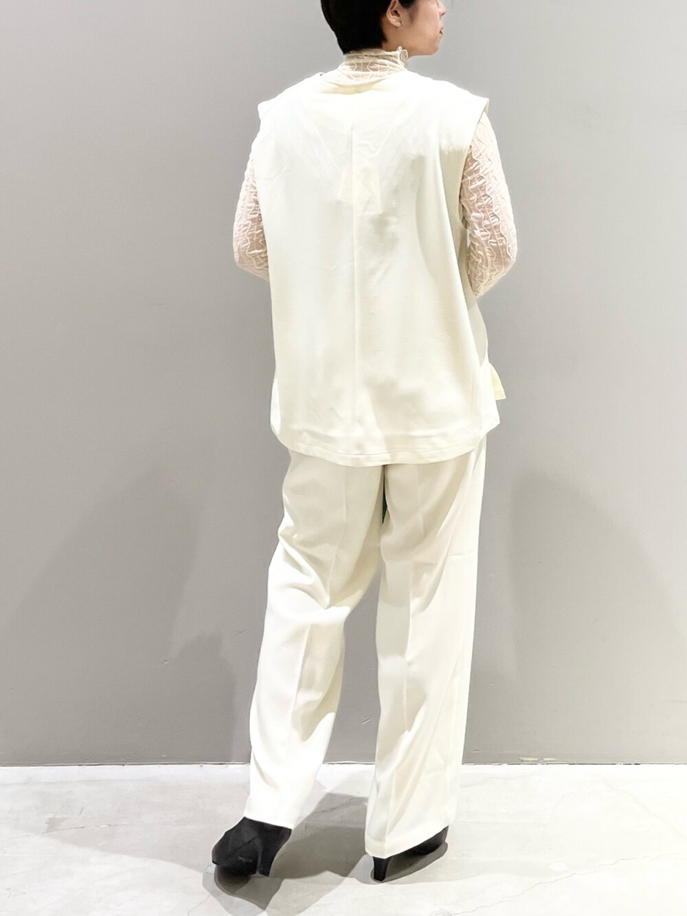 ホワイト系のベスト、グレー系のシューズ、グリーン系のバッグを着用したレディースの夏コーディネートの3枚目の写真