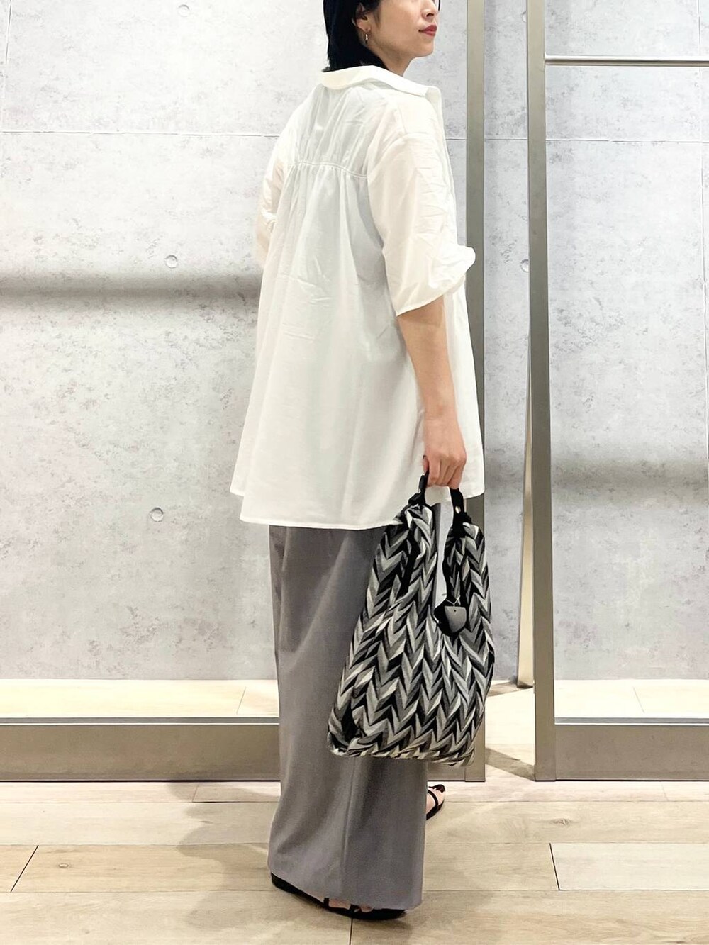 ブラック系のサンダル、ブラック系のハンドバッグ、グレー系のスラックスを着用したレディースの夏コーディネートの7枚目の写真