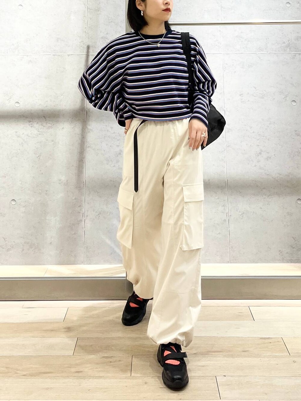 ブラック系のショルダーバッグ、ブルー系のTシャツ/カットソー、ホワイト系のカーゴパンツを着用したレディースの春コーディネートの4枚目の写真