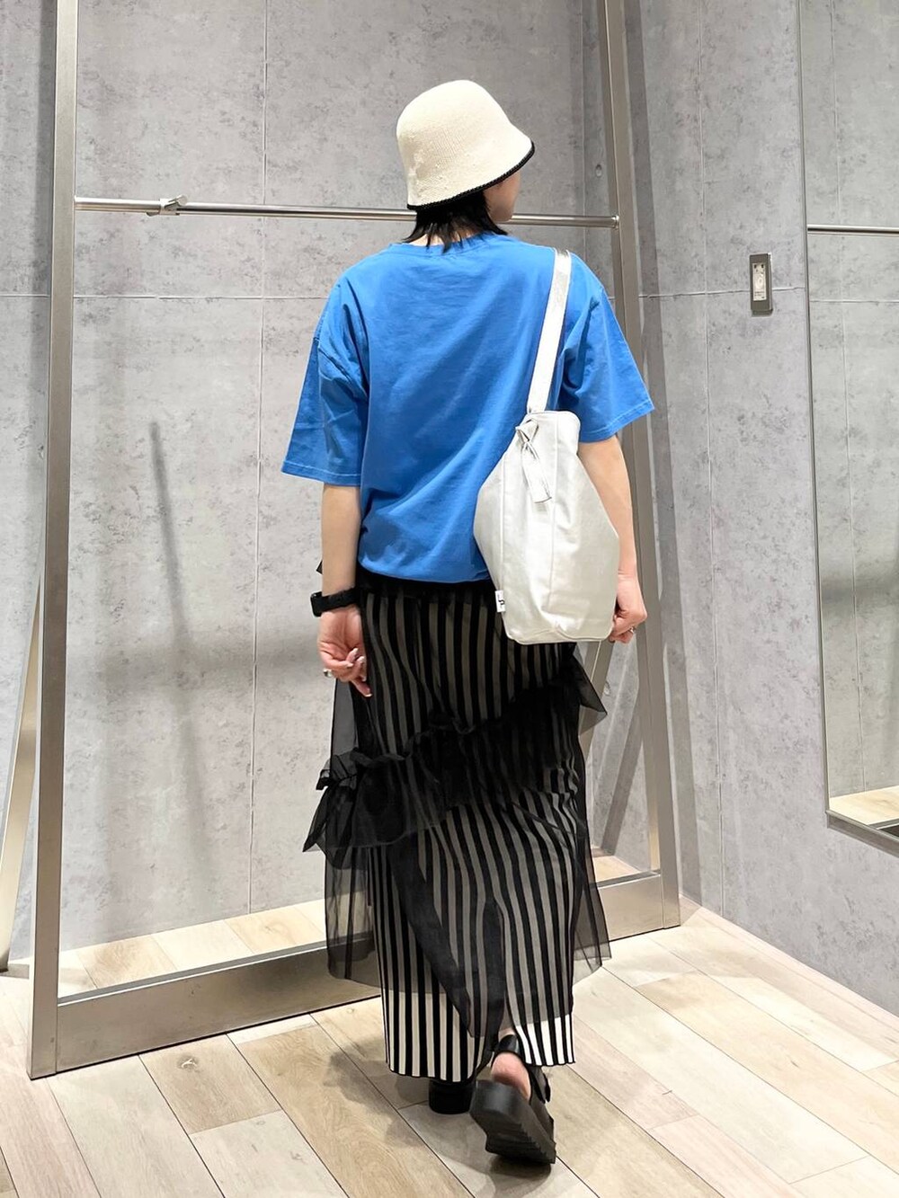 ホワイト系のスカート、ブルー系のTシャツ/カットソー、ブラック系のサンダルを着用したレディースの春コーディネートの5枚目の写真