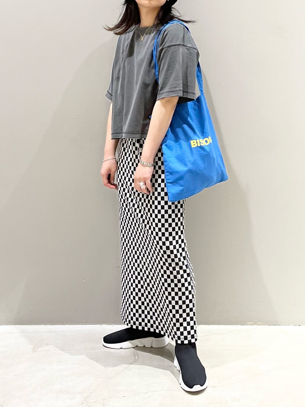 ブルー系のトートバッグ、ブラック系のシューズ、グレー系のTシャツ/カットソーを着用したレディースの秋コーディネートの2枚目の写真