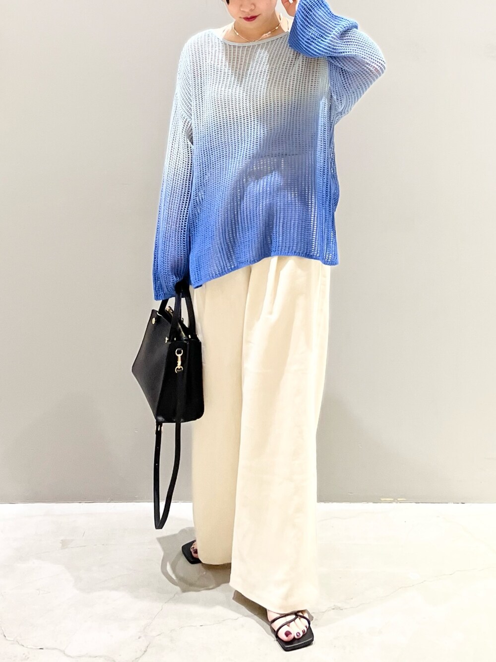 ブルー系のニット/セーター、ブラック系のショルダーバッグ、ブラック系のサンダルを着用したレディースの春コーディネートの8枚目の写真